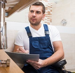 A man wearing overalls is seated on the floor with a clipboard, associated with Titan Exteriors. A man wearing overalls is seated on the floor with a clipboard, associated with Titan Exteriors.